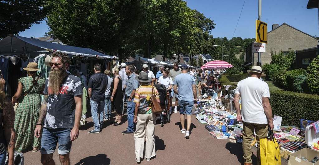 Diverse mensen lopen langs de kramen van markt in Wahlwiller. Het is zonnig weer en het is erg druk.