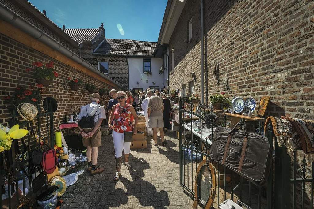 Er lopen mensen tussen de kramen van de markt van Wahlwiller. Het is zonnig weer en het is erg druk bij de kramen met diverse spullen.